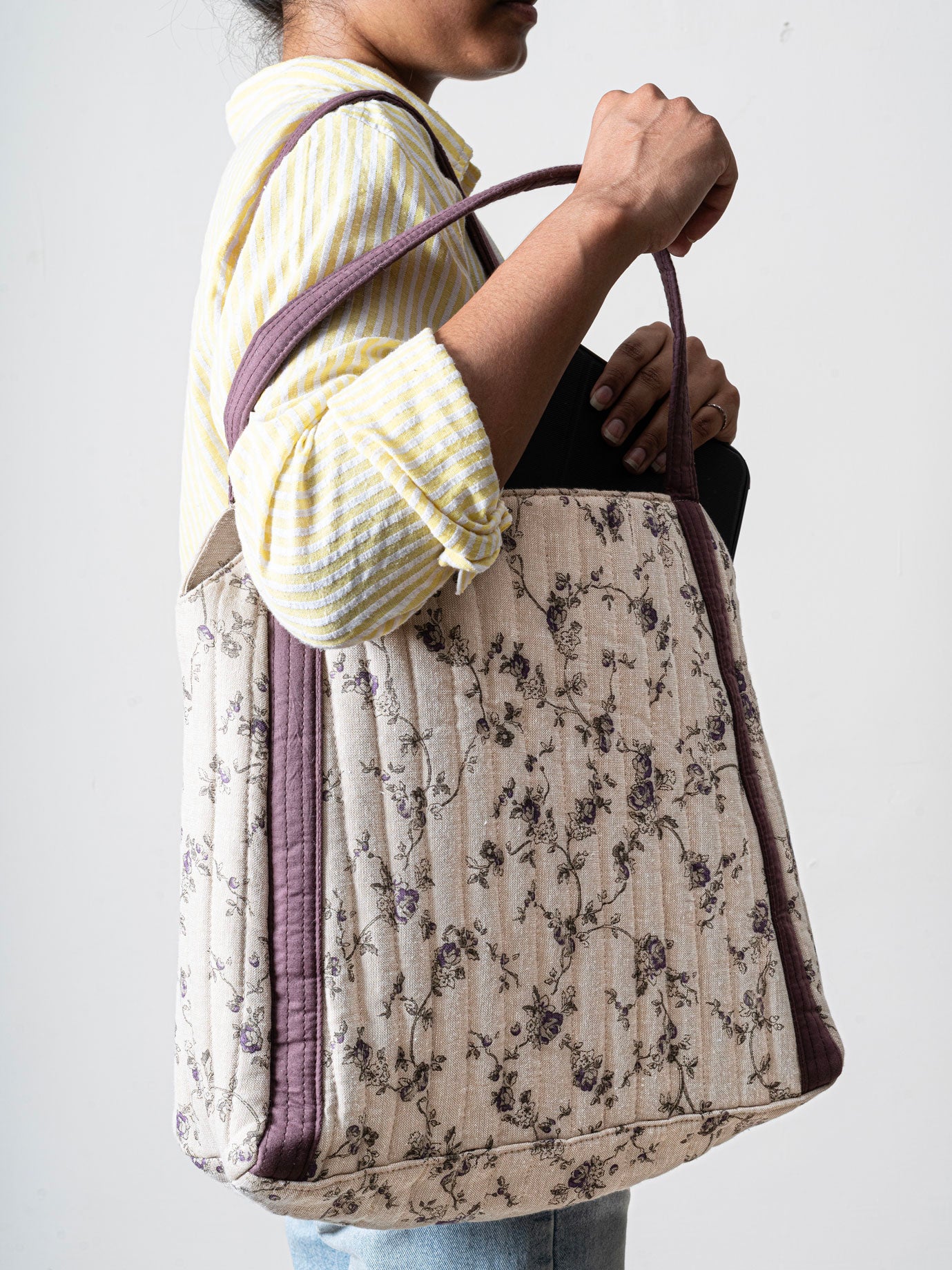 Person holding a floral-patterned quilted bag
