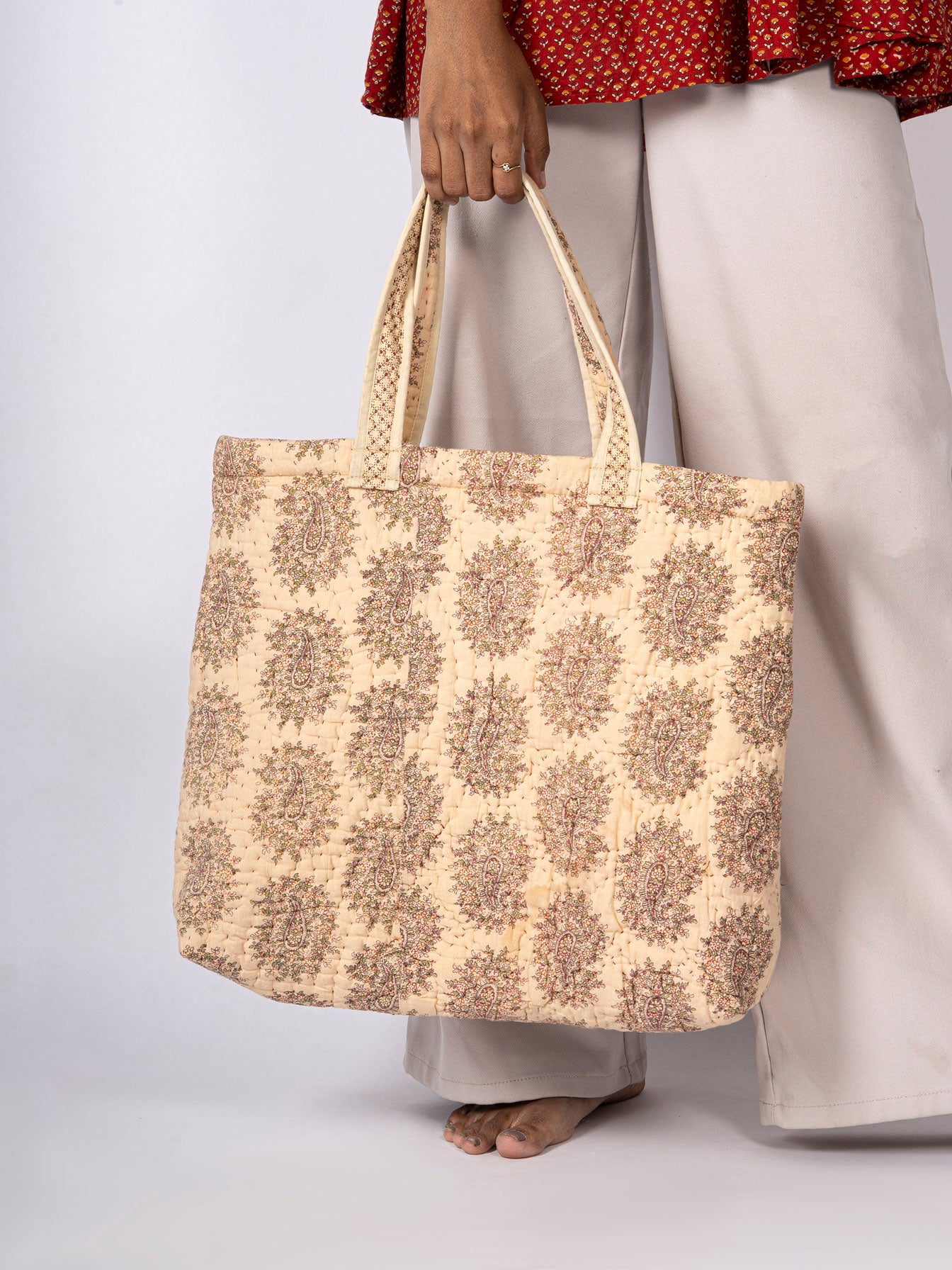 Woman holding a beige tote bag with floral pattern