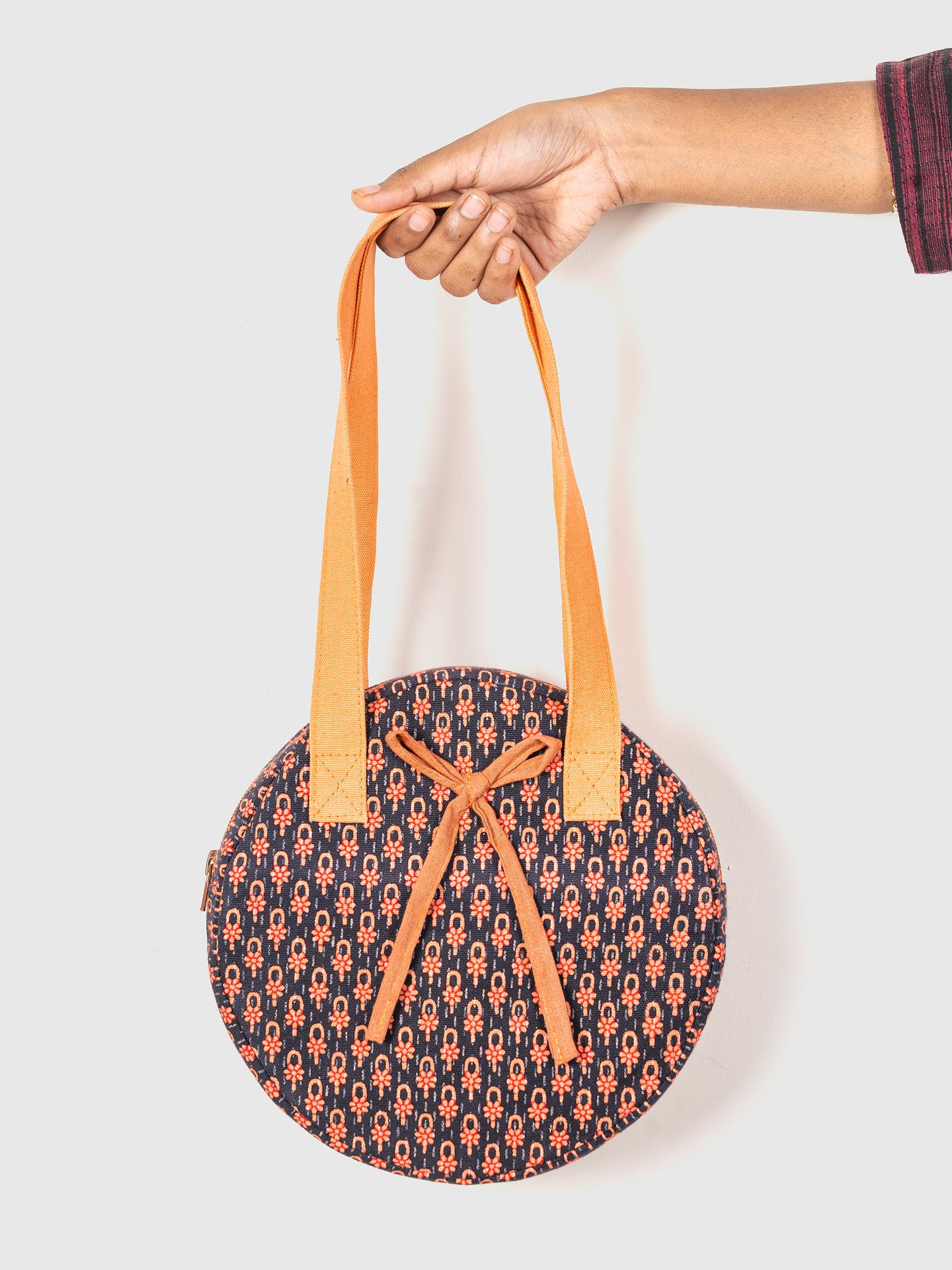 Round bag with orange handles and patterned design