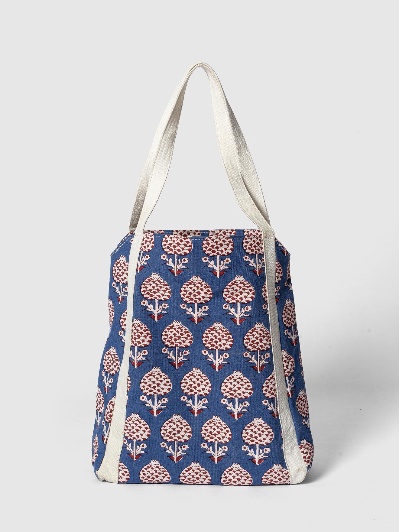 A blue block print tote with floral patterns, featuring natural cotton handles.